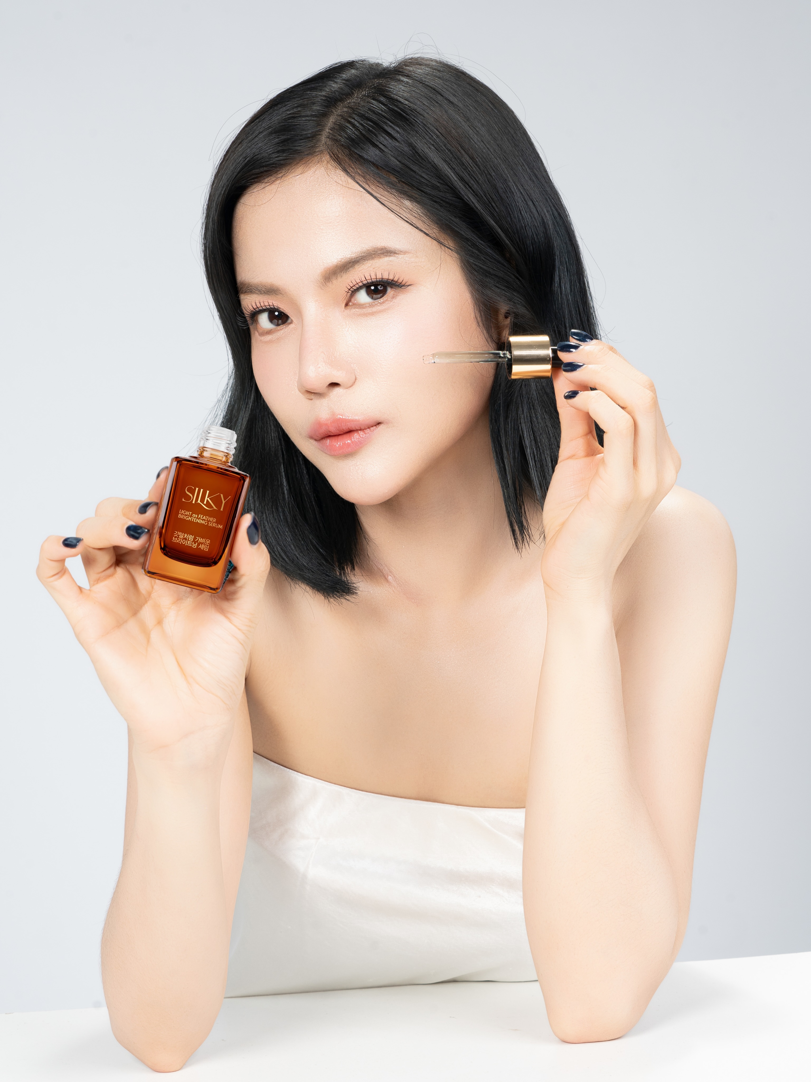 Woman holding SILKY serum and its applicator beside her face